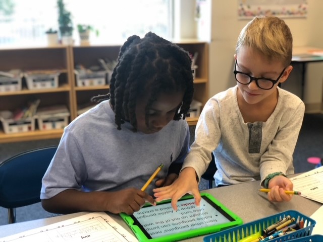 2 students working together on an ipad