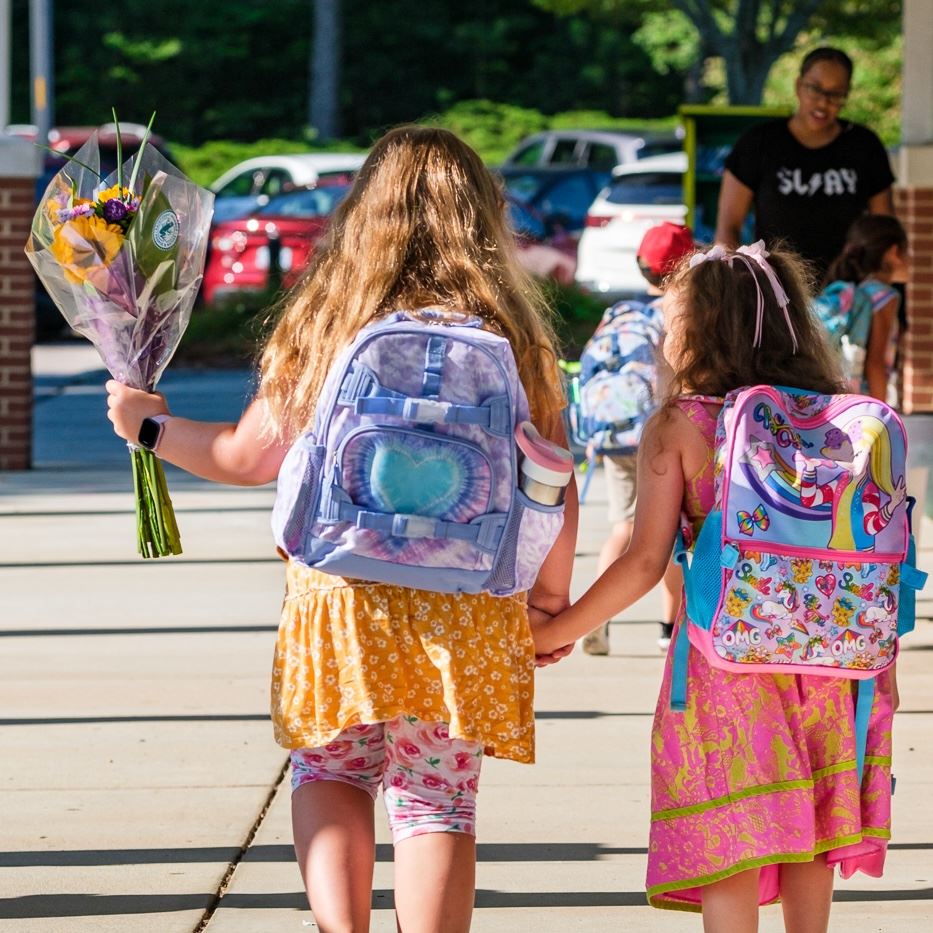  Two year-round students walk to class with flowers for their teacher