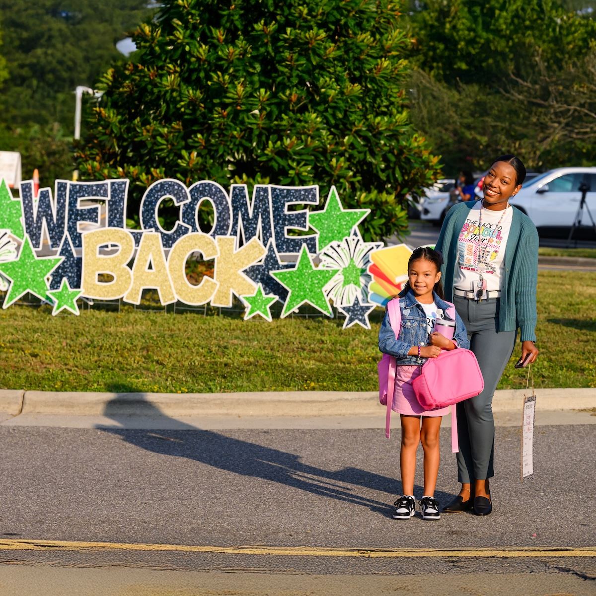  A parent and student pose in front of a "Welcome Back" sign