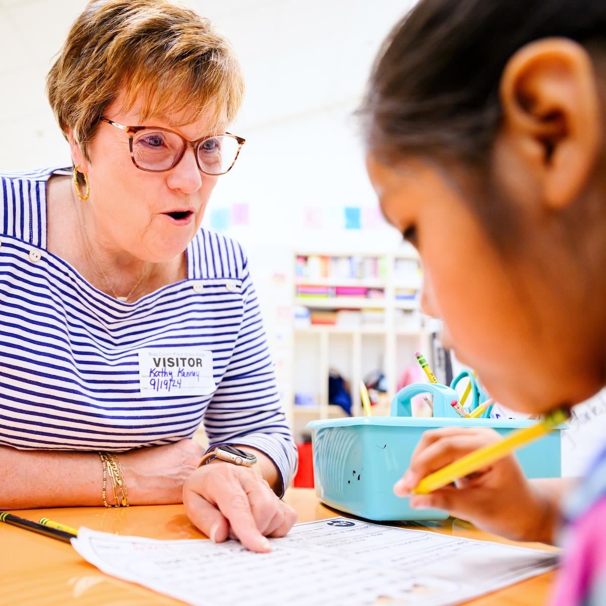  A school volunteer smiles while helping a student with class work