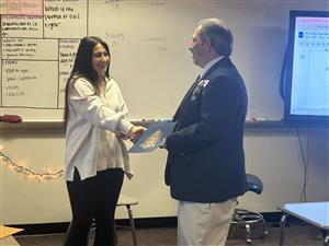 Ms. Cocoran accepts the certificate from a Sons of the American Revolution representative