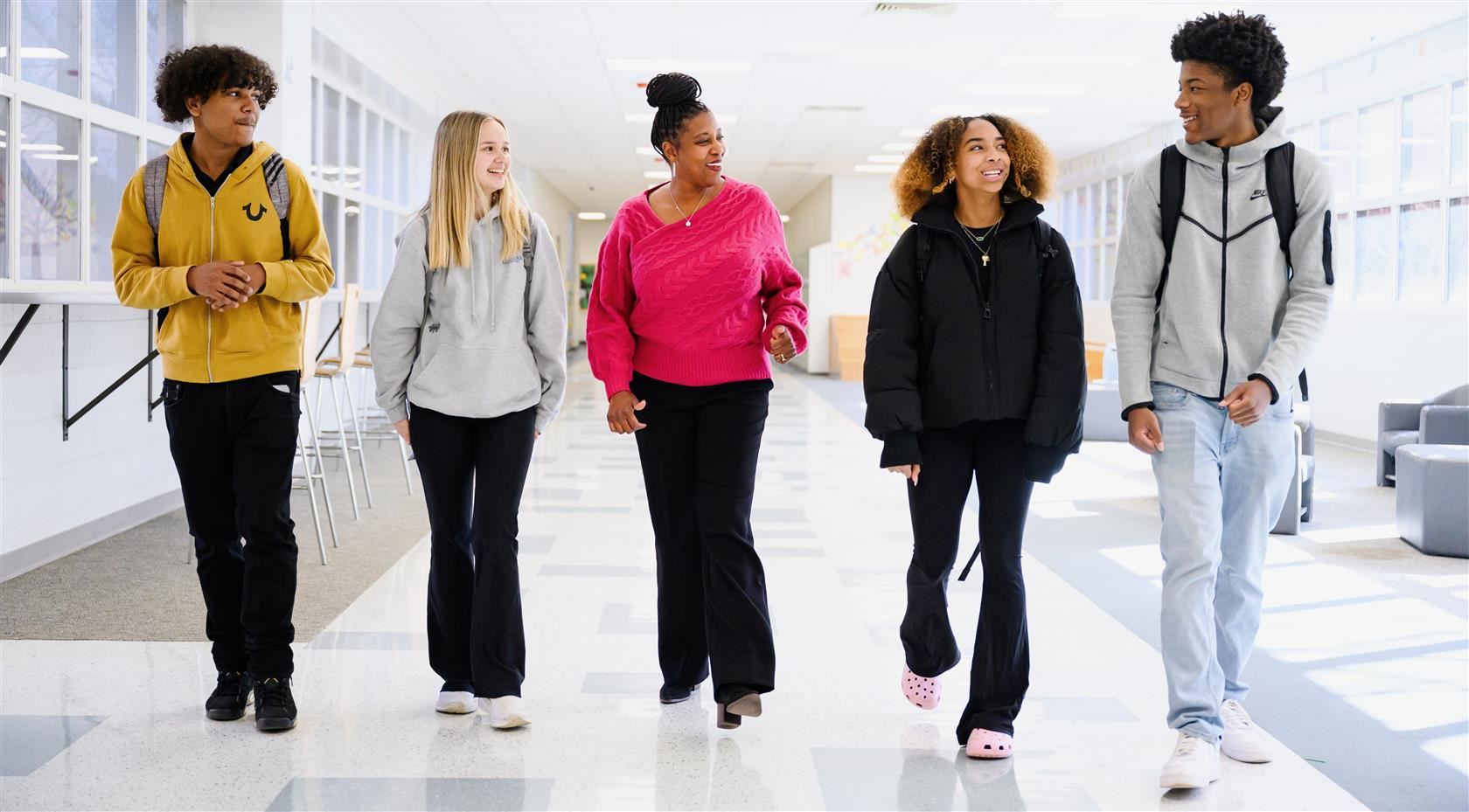 Principal walking down hall with four students