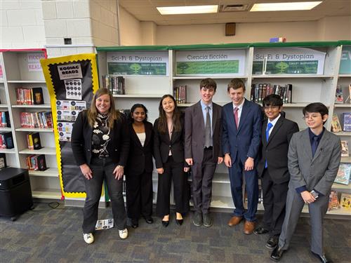 the debate team gathered in front of a book shelf