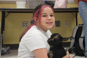 A student holding a baby goat and smiling