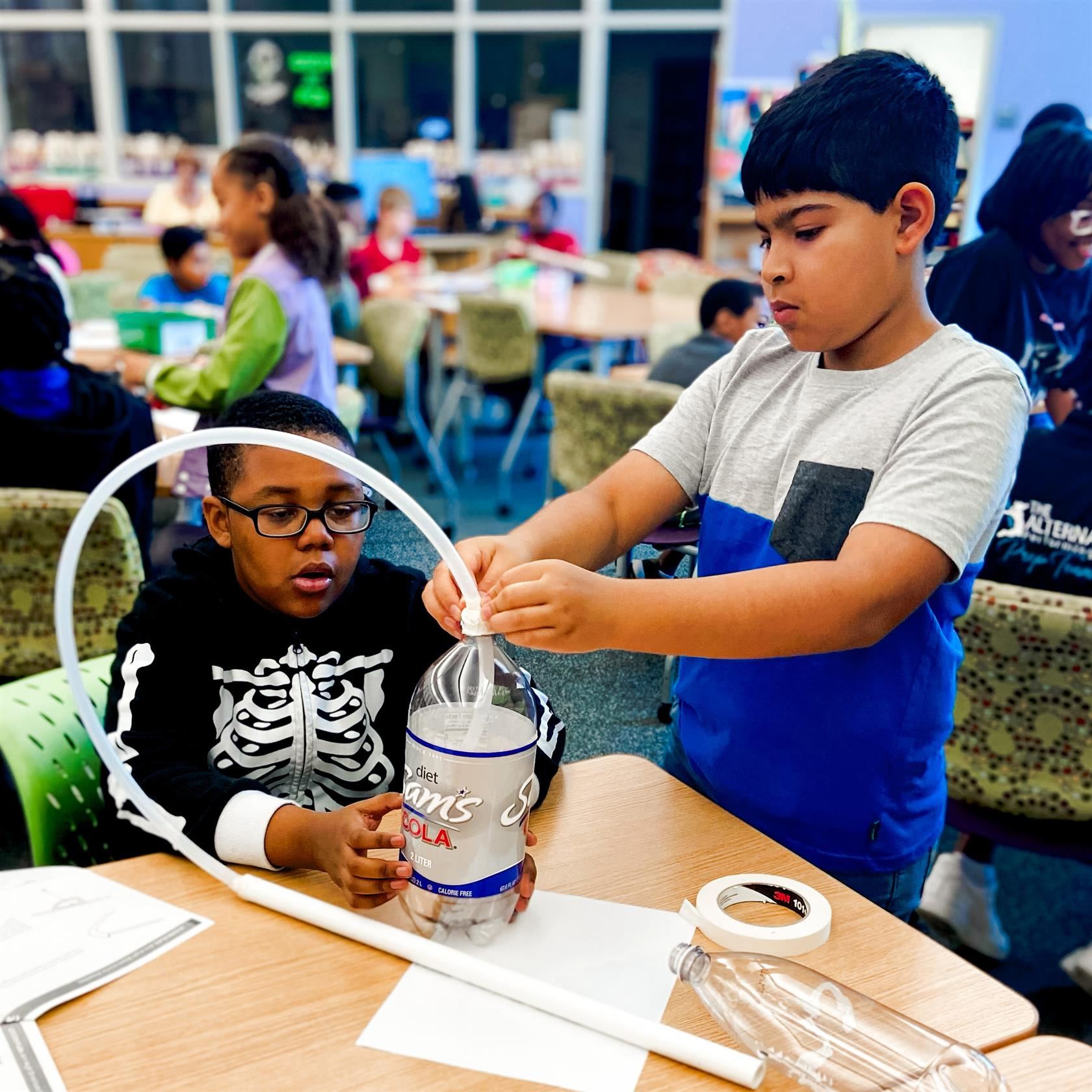  Two students perform a science experiment with bottles and tubes