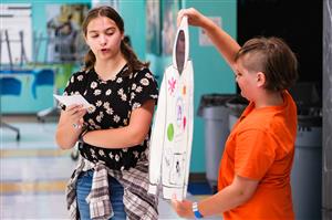 Girl Presenting a Project, boy holding the project