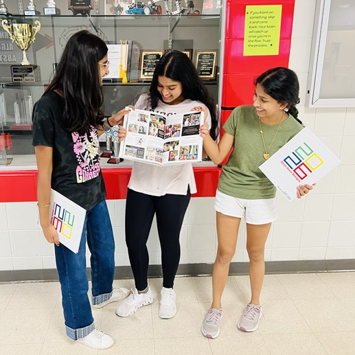  Group of girls holding the new yearbook and looking at pictures
