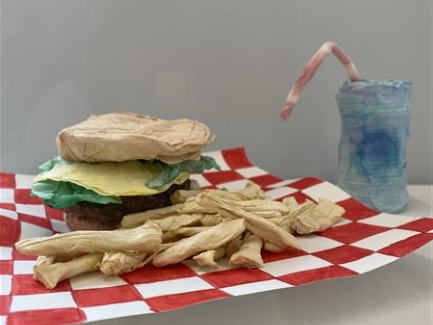 A sculpture of a burger and fries made out of papertowel, painted with watercolor. 