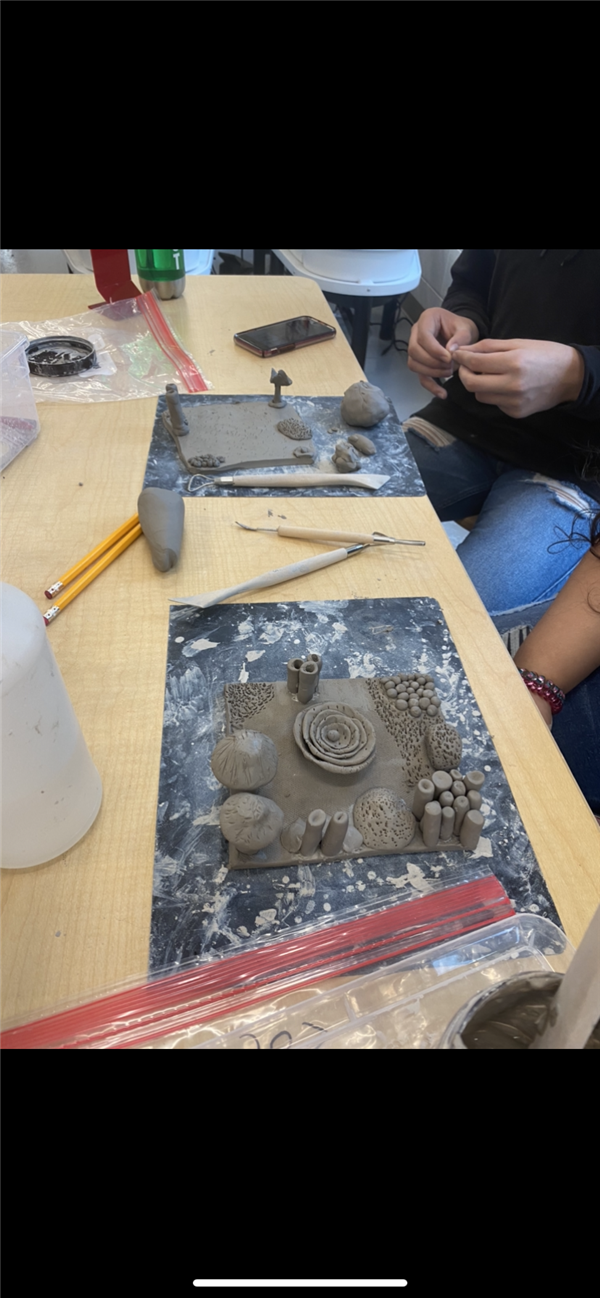 Students make swirls out of clay. 