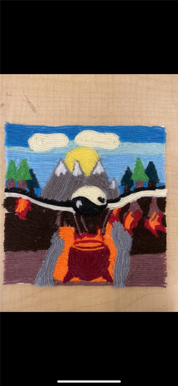 A yarn artwork of a mountain, a yinyang symbol, and sky. 